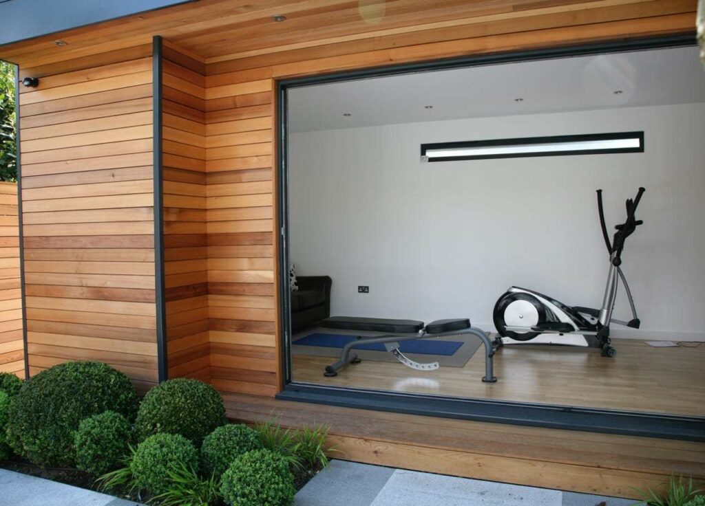 Beautiful cedar garden room, used as a garden gym with doors open from eDEN Garden Rooms